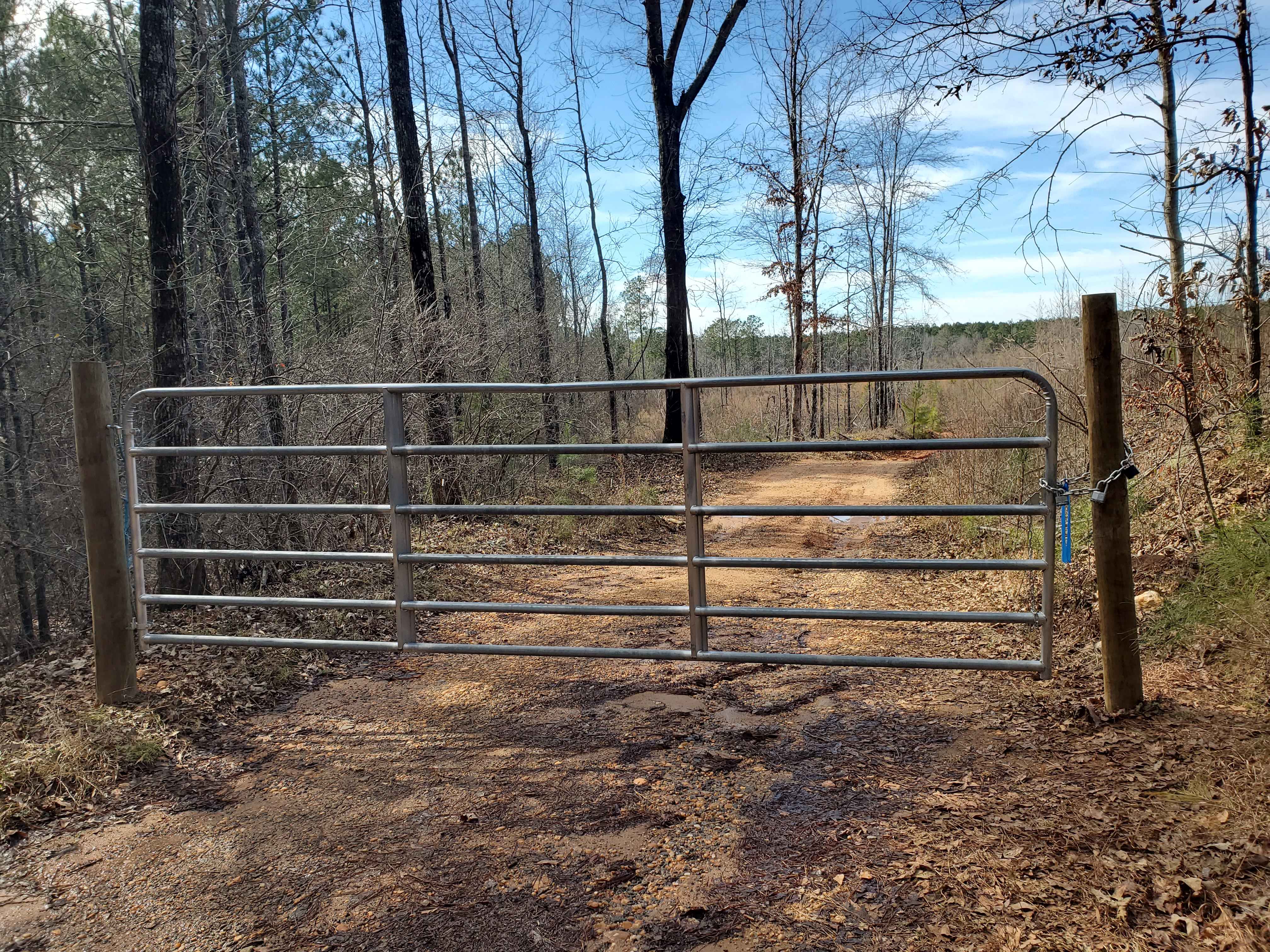 Locked gate on private multi-owner access road (owner's lock is on it)